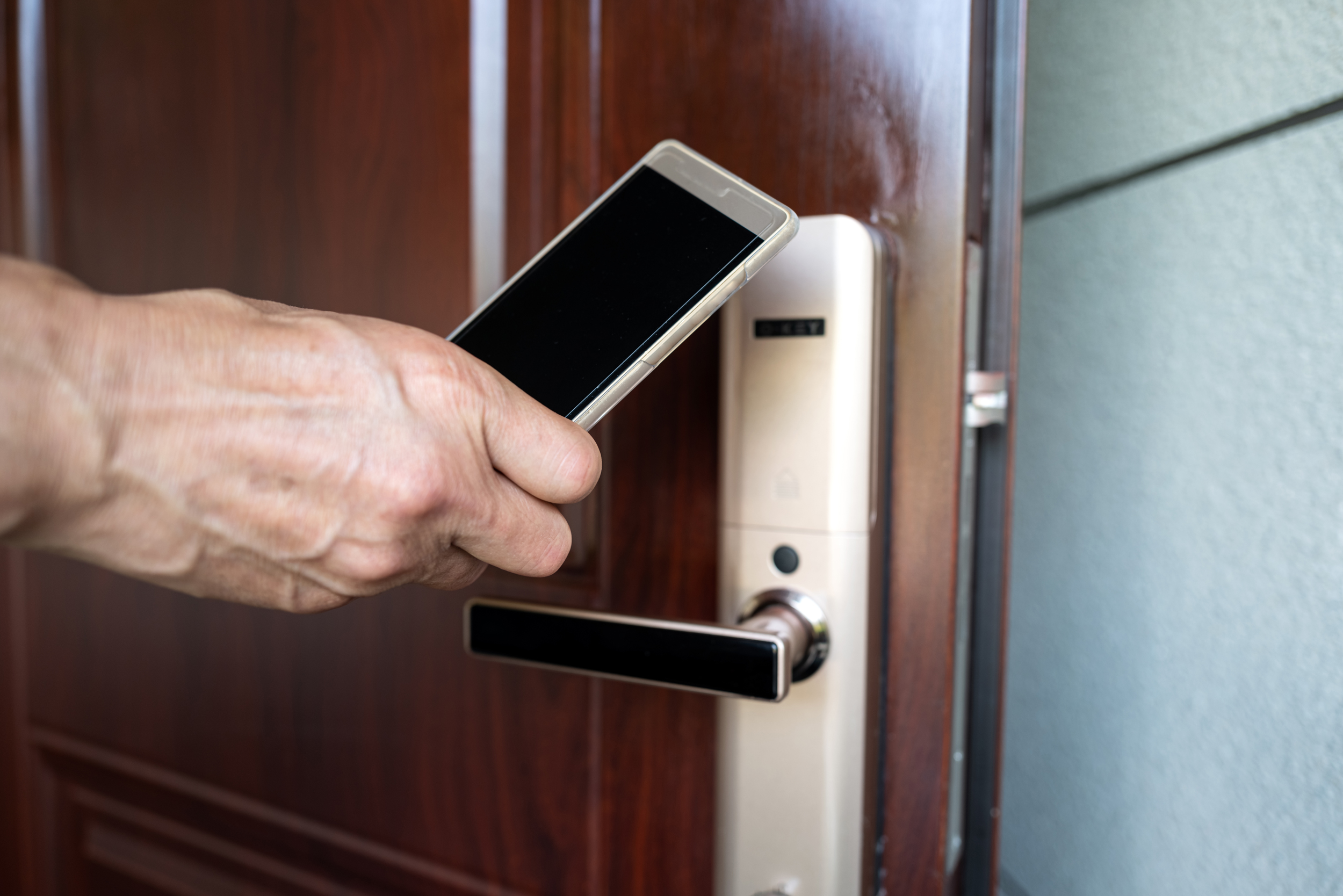 Human hand uses mobile phone to sense room door.